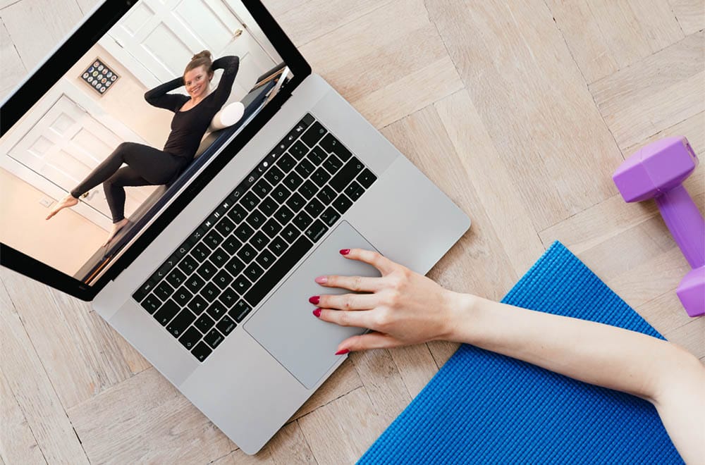 Woman watching an online Pilates class on her laptop